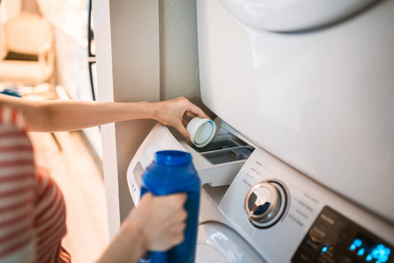 Close-up of a person pouring detergent into a front-loading washer, emphasizing household chores.